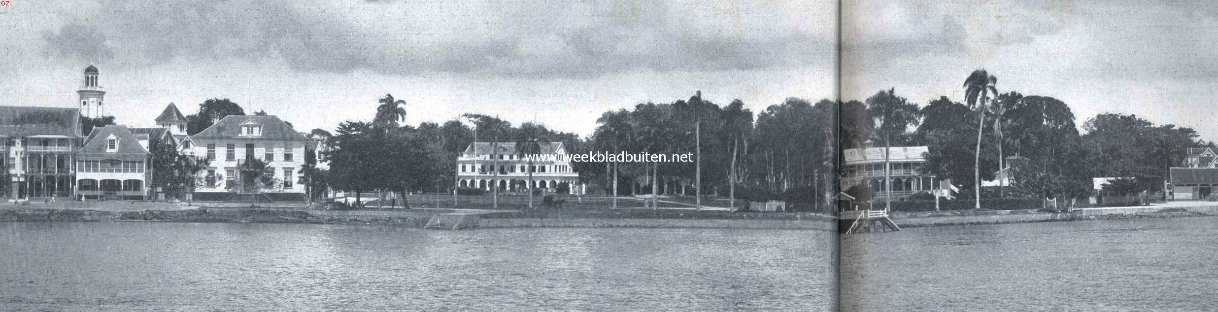 Paramaribo, van de rivierzijde gezien. Van links naar rechts: een drietal particuliere woningen; Gouvernementsplein, op den achtergrond het Gouvernementshuis; de Marinetrap; het Park (Sociteit). Verder naar rechts gebouwen, behoorende tot het Fort Zeelandia. Op den hoek, de vlag er boven, eenige oude fortgebouwen met zware muren, welke thans voor gevangenis dienen. In 't verschiet rechts enkele woningen van de voorstad Comb 1