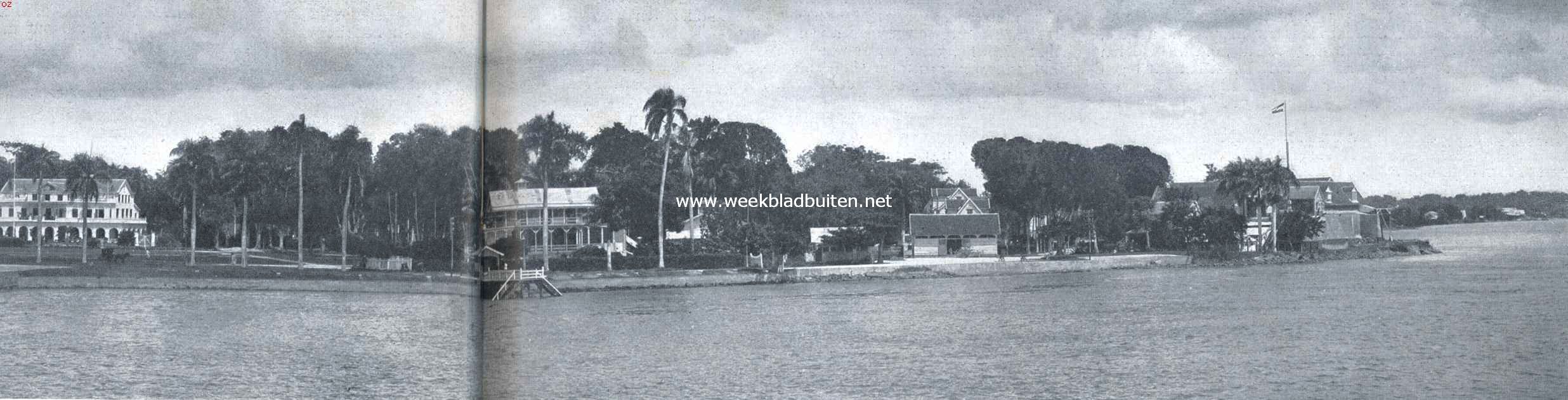 Paramaribo, van de rivierzijde gezien. Van links naar rechts: een drietal particuliere woningen; Gouvernementsplein, op den achtergrond het Gouvernementshuis; de Marinetrap; het Park (Sociteit). Verder naar rechts gebouwen, behoorende tot het Fort Zeelandia. Op den hoek, de vlag er boven, eenige oude fortgebouwen met zware muren, welke thans voor gevangenis dienen. In 't verschiet rechts enkele woningen van de voorstad Comb 2