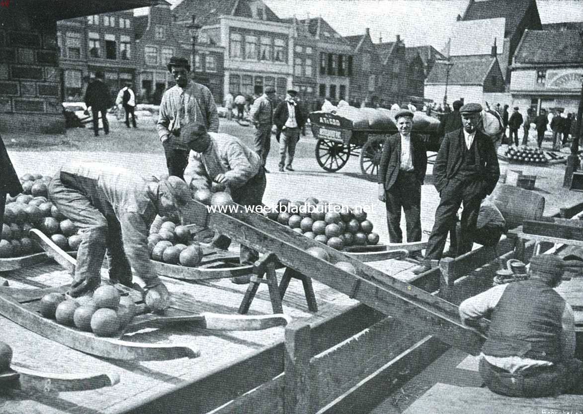 Waag en Kaasmarkt te Alkmaar. Het verschepen der kazen. Het reeds niet zeer fraaie beeld, dat de huizen op den achtergrond der markt op deze afbeelding vertoonen, is in de laatste jaren nog leelijker geworden door de doorbraak (links) waarover zooveel te doen is geweest en den bouw van een leelijk kaaspakhuis (rechts)