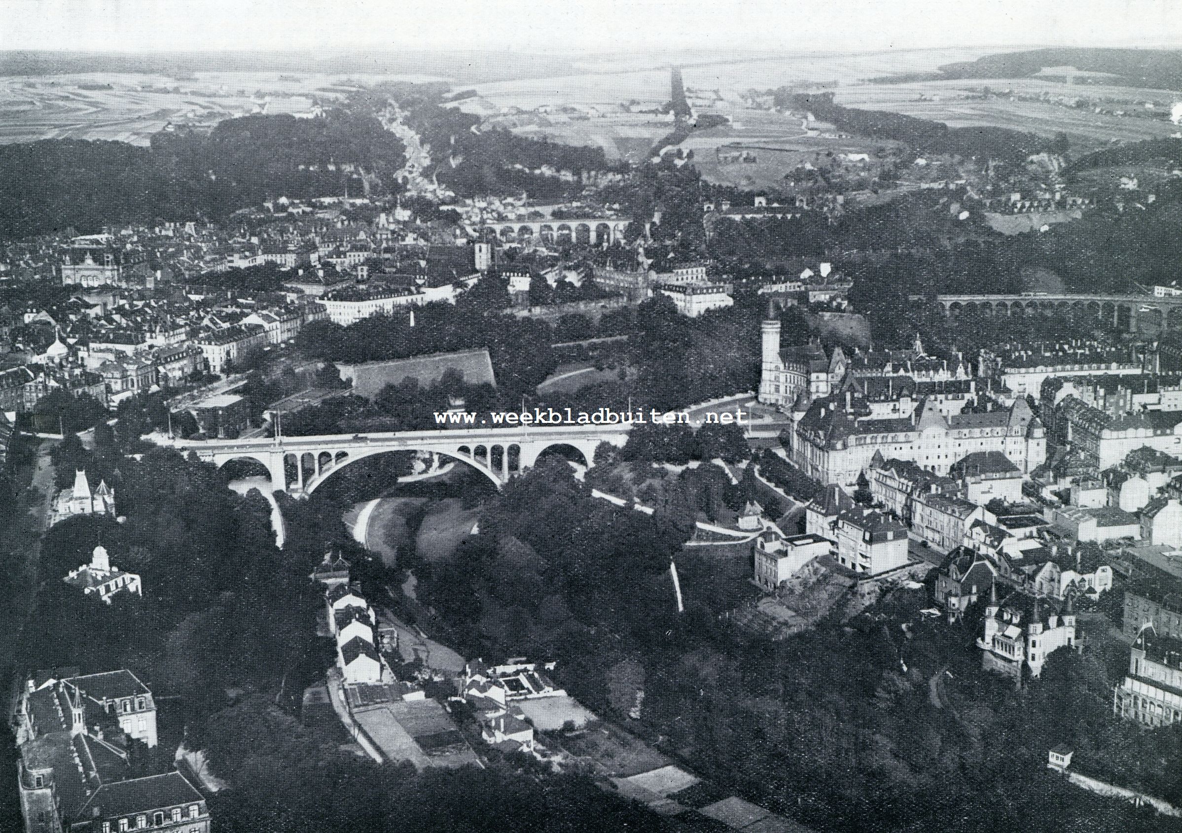 LUXEMBURG, DE HOOFDSTAD FAN HET GELIJKNAMIGE GROOTHERTOGDOM LUXEMBURG LIGT IN HET ZUIDEN, MIDDEN IN DAT DEEL DES LANDS HETWELK MEN GOEDLAND NOEMT. DE MACHTIGE ADOLFSBRUG OP DEN VOORGROND VERBINDT DE MODERNE VOORSTAD MET DE OUDE BINNENSTAD. (LUCHTFOTO)