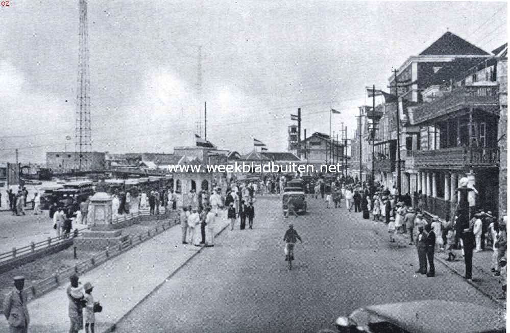 Curaao voorheen en thans. Het Brionplein te Willemstad. Links van den ingang der haven, genoemd naar Louis Brion (1782-1821), den beroemden Curaaonaar, die in 1805 een belangrijke rol speelde in de verdediging van het eiland tegen de Engelschen en tot 1820 de rechterhand was van Simon Bolivar, den bevrijder. - Op den achtergrond het Riffort; het hooge gebouw rechts is de woning van den apolstolischen vicaris